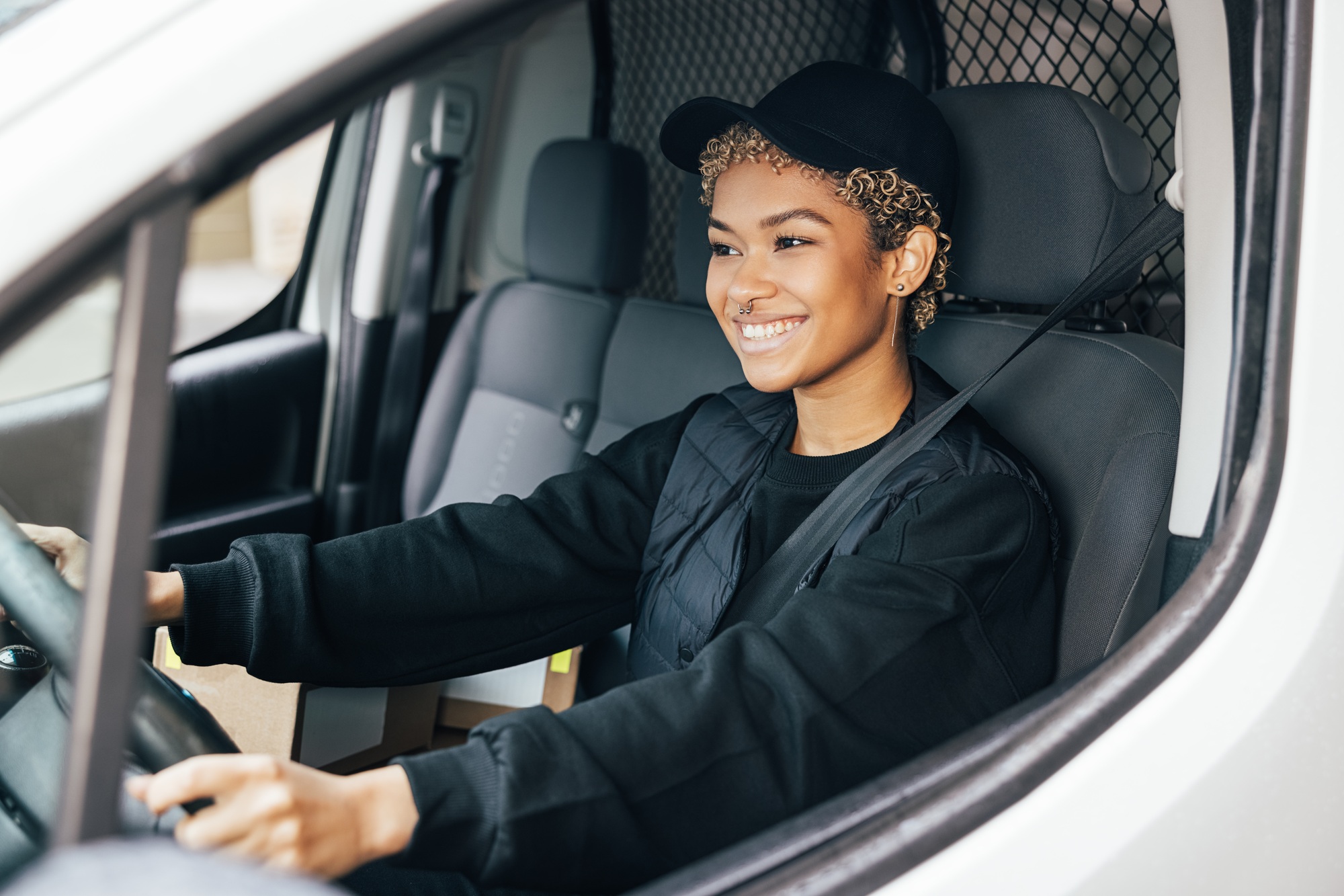 Portrait of a young woman working for a delivery service, sitting on a driver's seat
