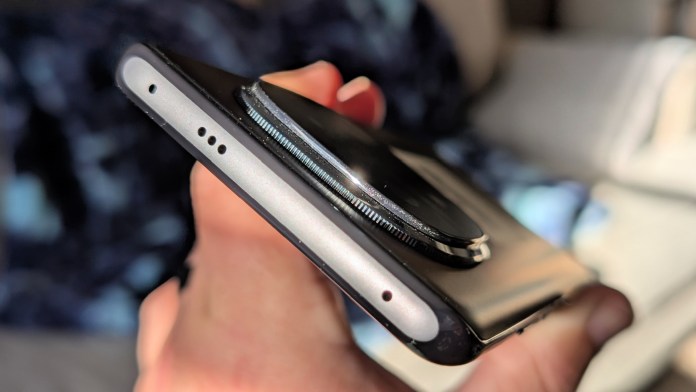 Close-up view of the Redmi Note 14+ Pro 5G smartphone held in a hand, showcasing its sleek design, camera lens, and ports.
