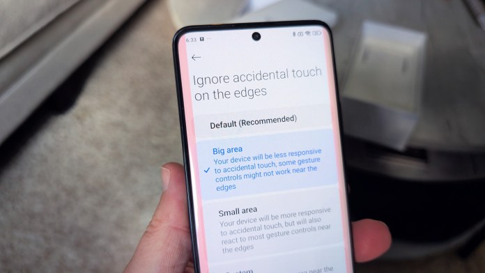 A close-up image of a smartphone screen displaying settings for 'Ignore accidental touch on the edges,' showcasing options for 'Default (Recommended),' 'Big area,' and 'Small area.'