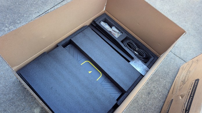 An open box containing the Yarbo Core components, showing packaging materials, a power cable, and other accessories neatly arranged inside.