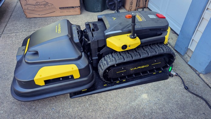 A modular yard robot called the Yarbo Core, designed for outdoor maintenance, featuring a tracked base and various attachments for snow blowing, lawn mowing, and leaf blowing.