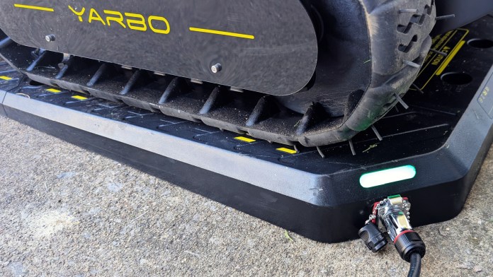 Close-up of the Yarbo Core robot on its charging dock, showing the tire and connectors.