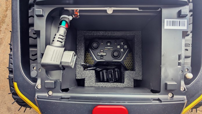 An overhead view of the compartment inside the Yarbo Core yard robot, showcasing the remote control and wiring.