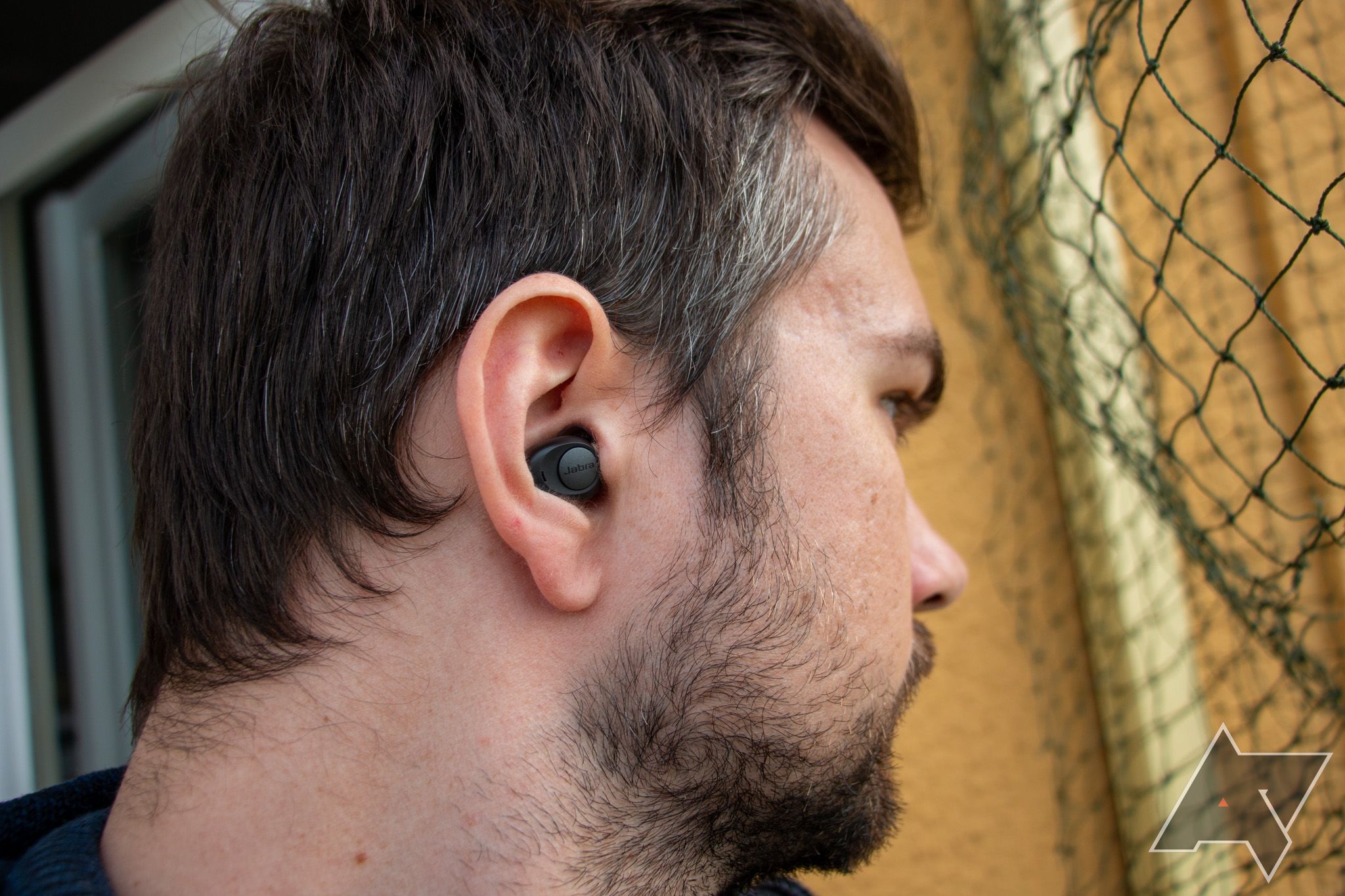 Head shot of a man looking into the distance to the side, with the Jabra Enhance Plus hearable visible in his ear