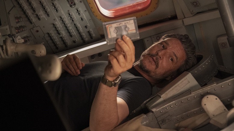 Joel holding a cassette tape laying horizontally in The Last of Us