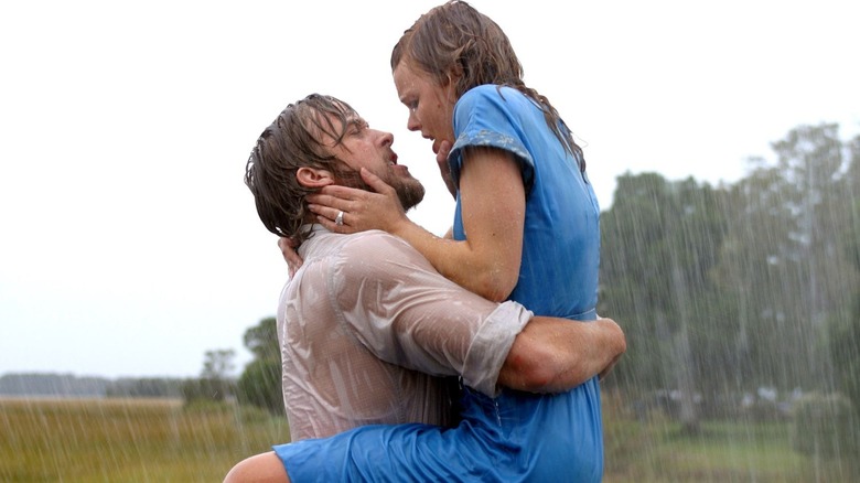 Noah (Ryan Gosling) carries Allie (Rachel McAdams), who passionately holds his head in her hands as they nearly kiss in the pouring rain