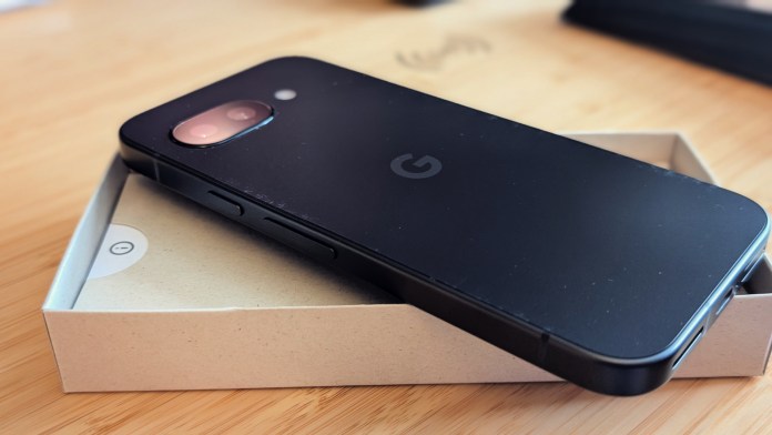 The Google Pixel 9A phone resting on its minimalist packaging, showcasing its sleek design and camera cutout.