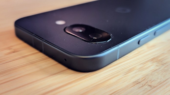 Close-up view of the Google Pixel 9A smartphone showing the camera module and side buttons on a wooden surface.