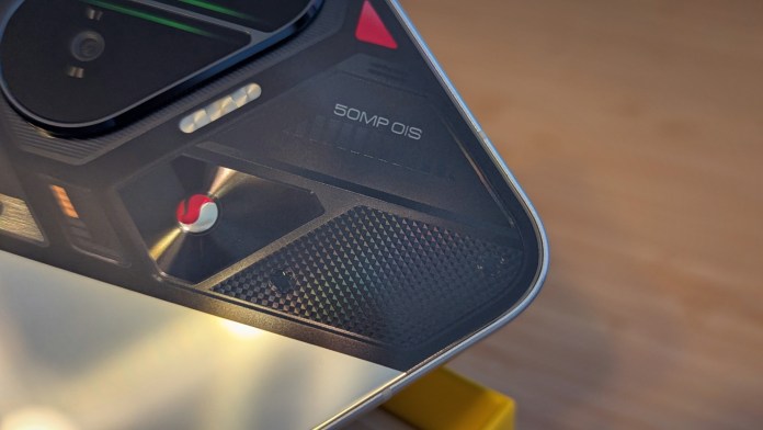 Close-up of the POCO F7 smartphone's camera module, highlighting the 50MP sensor and OIS feature on a textured surface.
