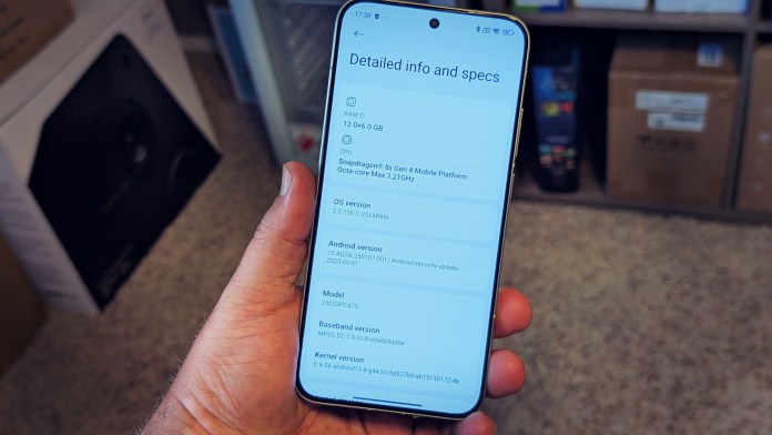 A person holding a smartphone displaying detailed specifications, including RAM, CPU, OS version, and Android version.