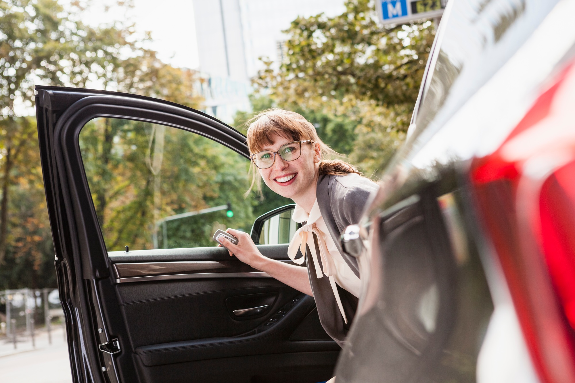 Portrait of smiling businesswoman getting off her car