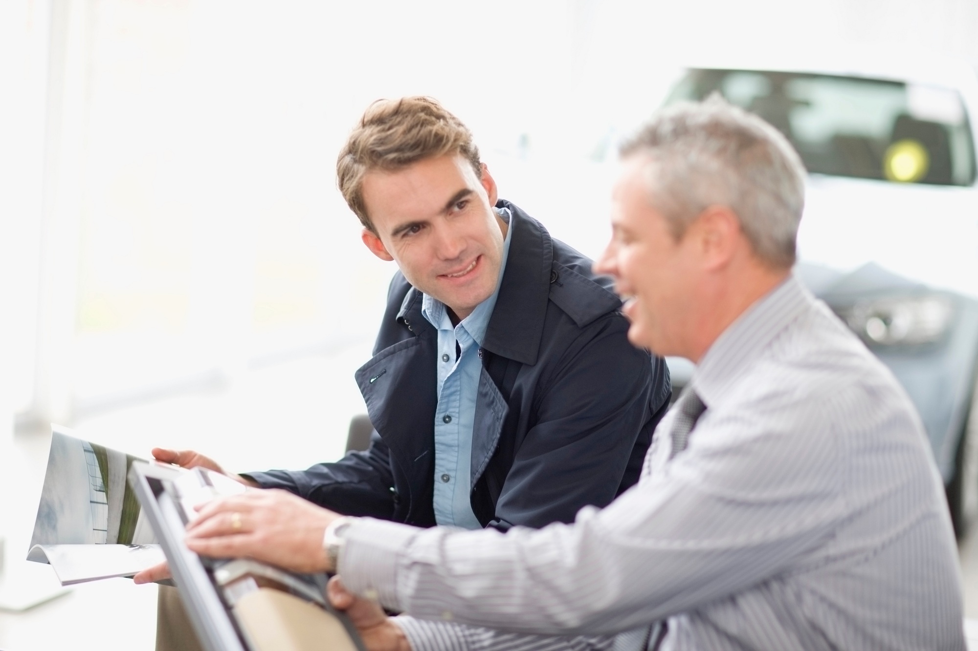 Salesman showing off car in showroom