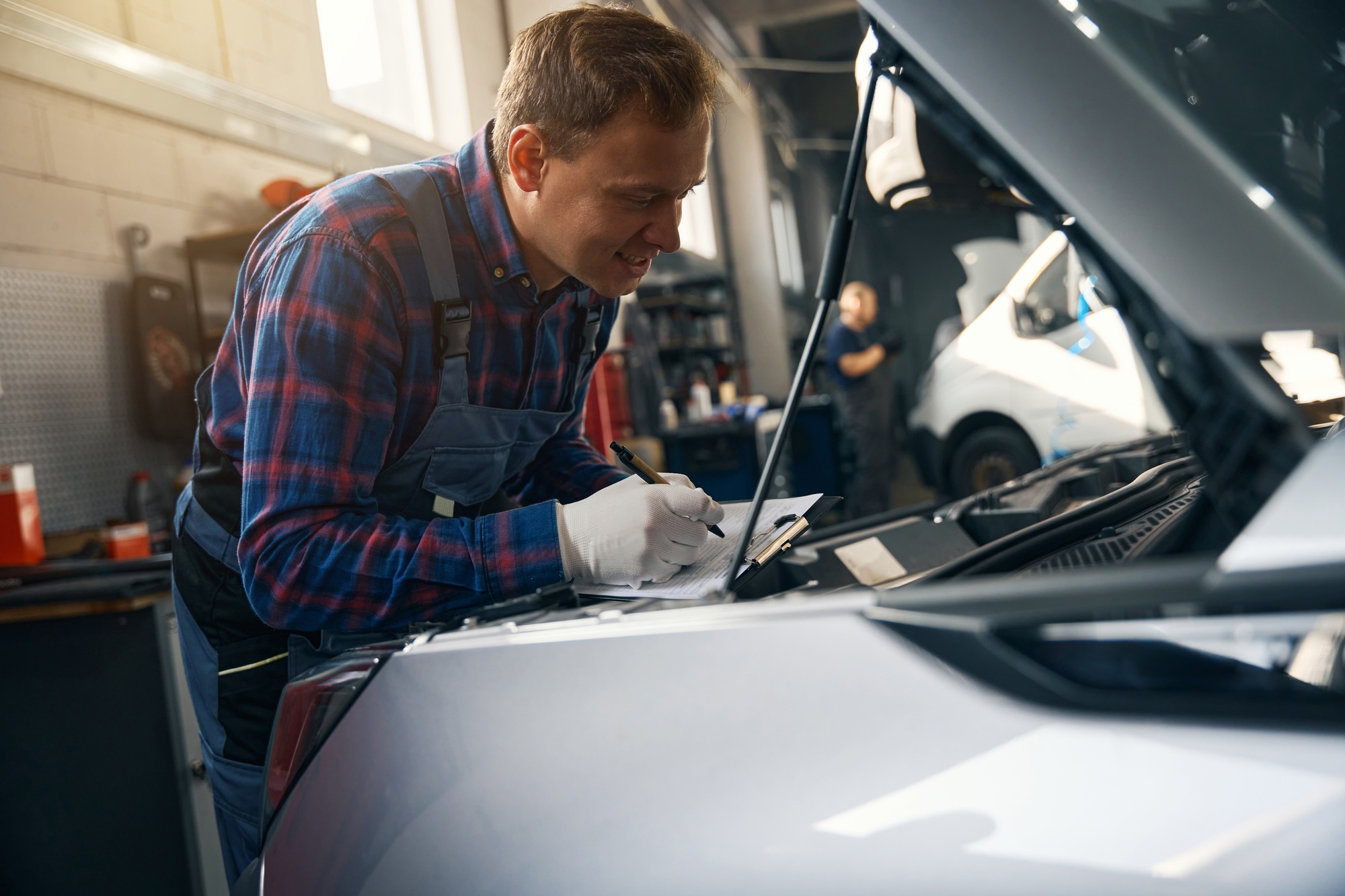 Young man writing vehicle engine performance indicators
