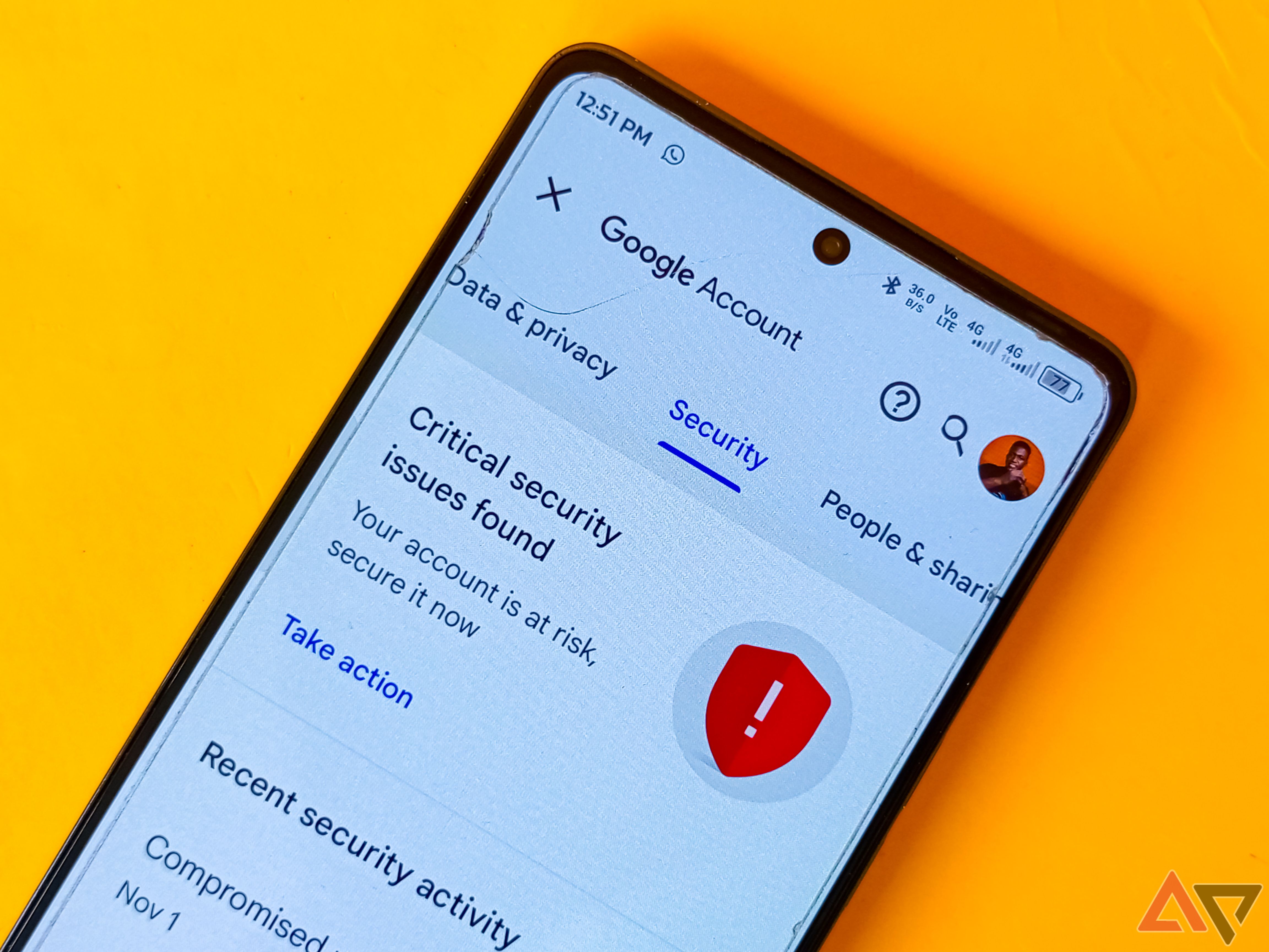 The Google account security settings screen captured on a phone placed on a yellow background. 