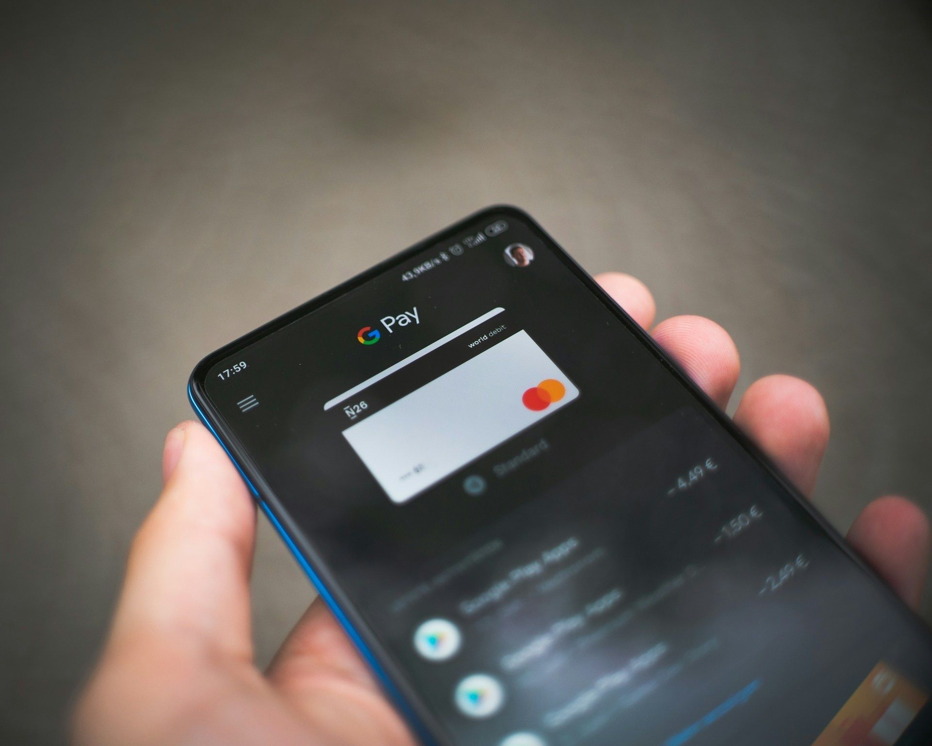 Hand holding phone showing bank card added to Google Pay app