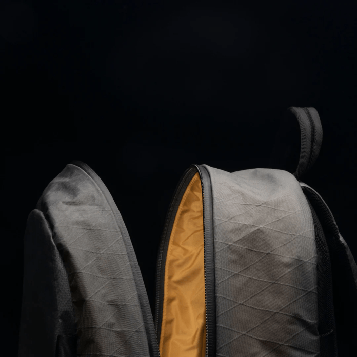Close-up of the open compartment of a gray backpack with a yellow interior, showcasing its design and organizational features.