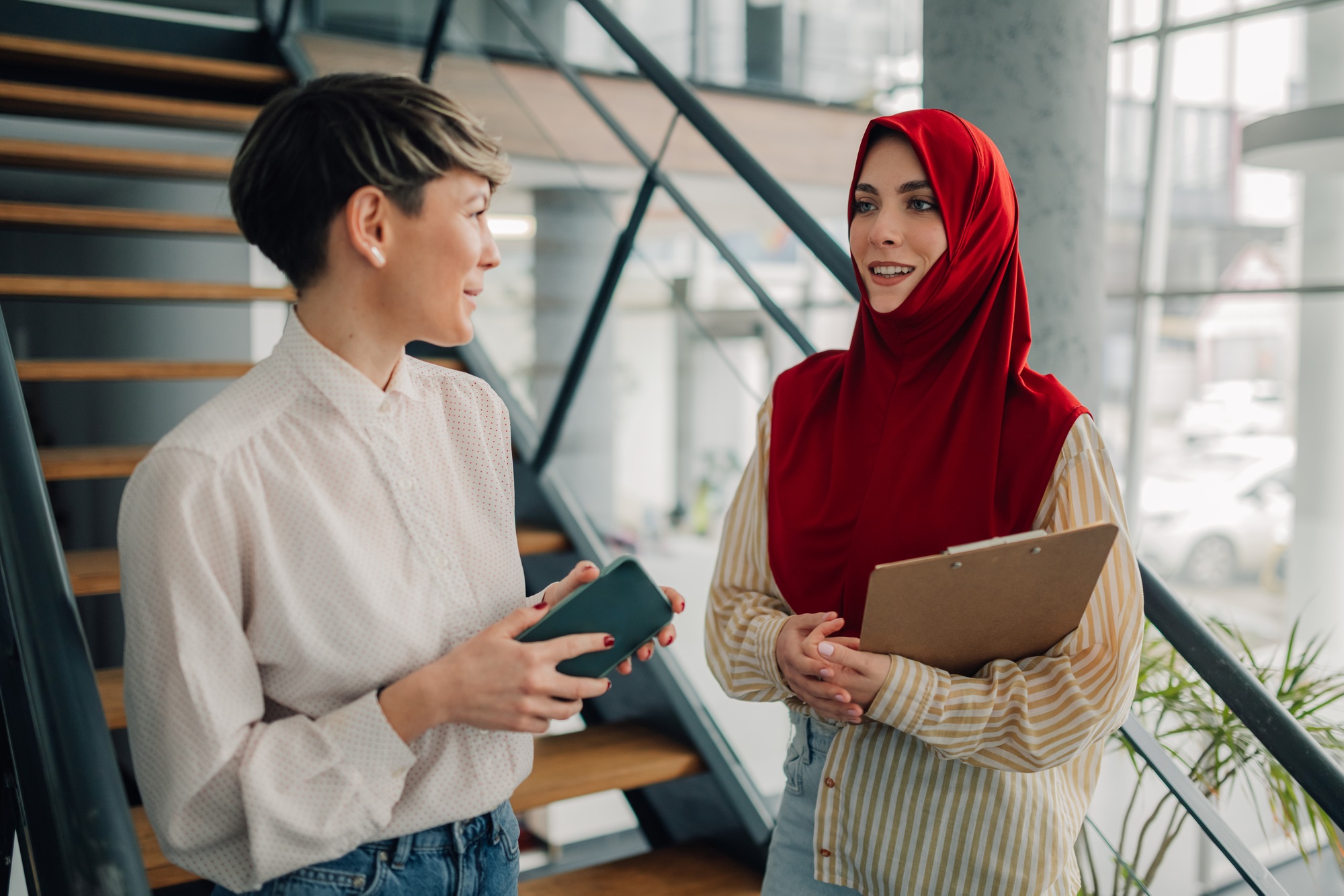 Businesswomen talking and smiling on office stairs
