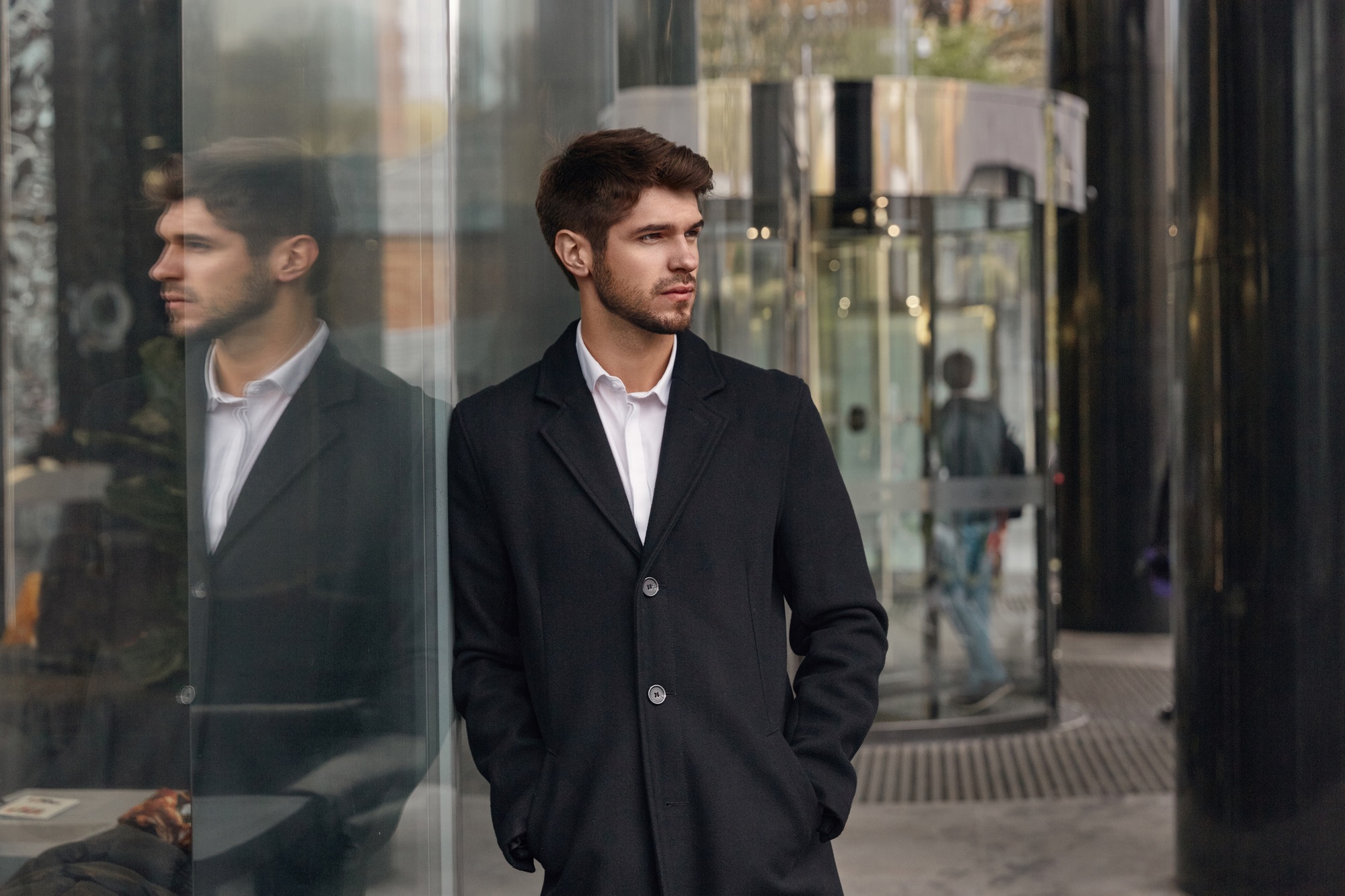 Serious business man standing by glass building