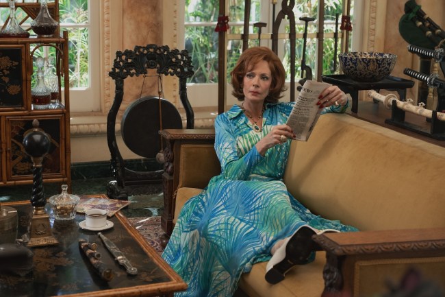 Allison Janney in 'Palm Royale' Season 2, shown reading the newspaper in a blue and green dress with a fern-like pattern